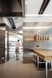 A modern commercial kitchen with stainless steel appliances and countertops, featuring sleek design and efficient layout.