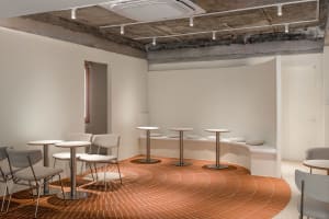 A minimalist coffee shop with brick-tile flooring and white tables and chairs.