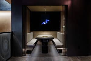 A modern restaurant booth with white leather upholstery and a black table with a central air vent.