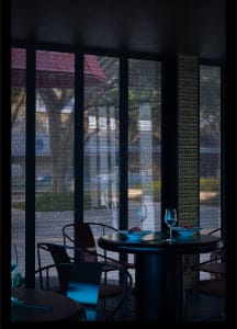 A modern restaurant interior with glass walls, a table, and chairs.