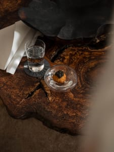 A wooden table topped with a bowl of food and a glass of water.