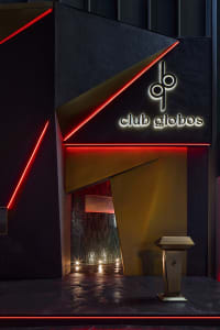 Modern nightclub exterior with metallic accents, glass panels, and LED lighting at night.