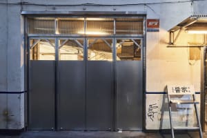 A metal storefront with an industrial design style, featuring large glass panels and a rustic exterior.