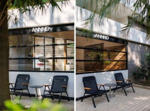 Modern glass and concrete exterior of a coffee shop, featuring outdoor seating.