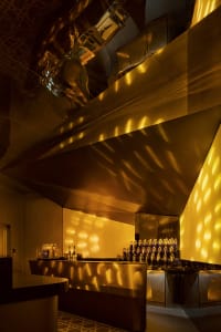 A modern retail bar with a metallic finish, featuring geometric lighting and sleek design elements.