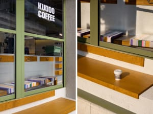 An exterior view of a coffee shop with a wooden sill, showing the branding and window seats.