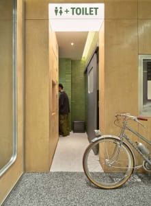 A modern toilet with wooden walls, tiled walls, and carpeted flooring.