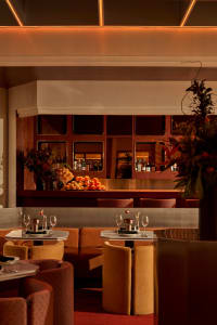 A modern restaurant bar with metal tables, leather seating, and walnut accents.