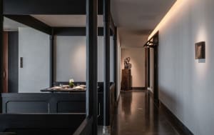 A minimalist dining room with dark wooden tables and chairs, clean lines, and a single flower arrangement on the table.