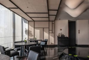 Modern restaurant interior featuring concrete and glass materials with black accents and minimalist design.