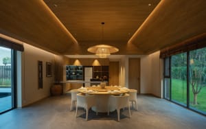Modern dining room featuring a round table surrounded by white chairs, with a wooden ceiling and floor.