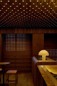 A modern bar interior with wooden finishes and a mushroom-shaped lamp on the counter.