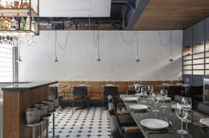 A modern industrial restaurant interior with metal tables, tile flooring, and industrial pendant lights.