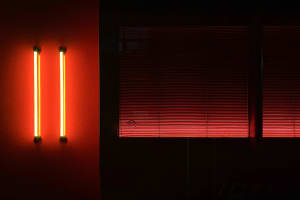 A minimalist interior design featuring fluorescent lights, blinds, and a window.