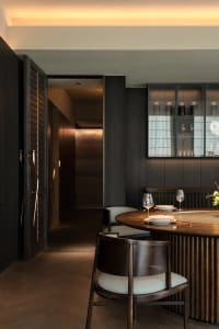 Modern dining room with walnut wood furniture and dark wooden paneling.