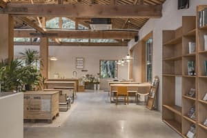 Modern industrial coffee roastery office space with wooden tables, concrete floor, and exposed wooden beams