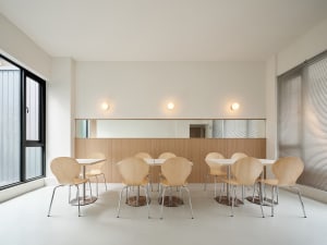 A minimalist cafeteria featuring wooden tables and chairs.