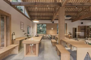 A modern cafe interior with wooden furniture and a long central table.