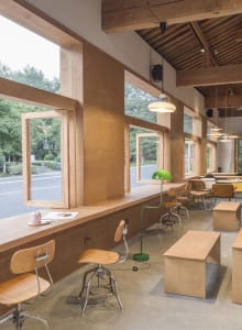 A modern cafe interior with large windows and wooden seating.
