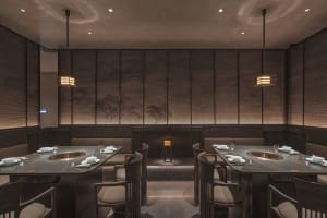 Modern restaurant interior with dark oak tables, white fabric seating, and minimalist lighting