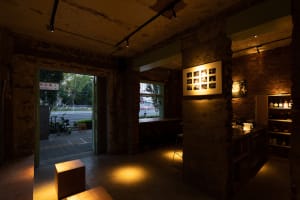 Interior of a cozy, industrial-style cafe-bar with exposed brick walls, concrete flooring, and dim lighting.