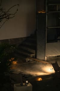 Concrete stairs leading down in a dark, smoky residential area with a small fire in the foreground.