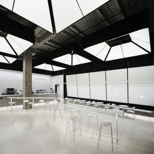 View of a minimalist coffee shop interior with concrete walls and a white ceiling.