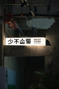 A minimalist signage with illuminated characters on a dark, industrial background.