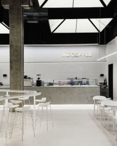 Modern and minimalist coffee shop with white metallic furniture and fixtures.