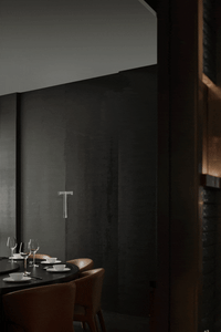 A modern restaurant interior featuring a black concrete wall and wooden furniture.
