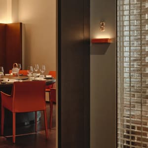 Modern restaurant dining room featuring glass walls, wooden accents, and leather seating.