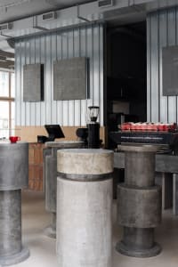 Modern coffee shop with industrial design featuring concrete columns and minimalist decor.