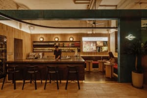A modern restaurant interior featuring a wooden counter and a cozy seating area.