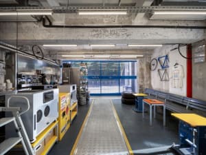 A spacious industrial workshop with concrete walls, metal shelving, and various tools and equipment.