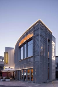 Modern commercial retail storefront with metal netting cladding and illuminated signage