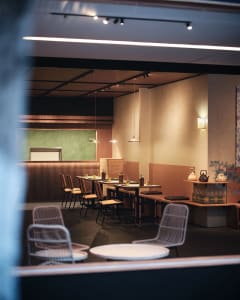 A modern restaurant interior with tables, chairs, and design elements like wood, concrete, and metal.