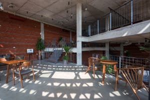 Concrete floors, exposed brick walls, and wooden furniture in an industrial-style coffee shop interior.