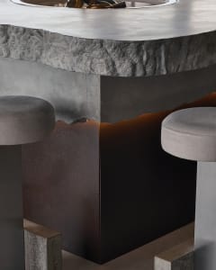 Industrial-style concrete bar counter with stools and lighting.