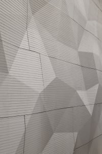 Modern architectural facade featuring a textured concrete surface with geometric patterns.