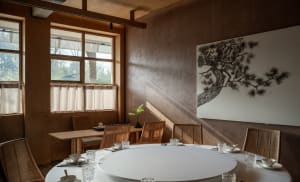 Industrial-themed restaurant interior with wooden furniture and large window.