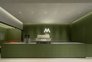 A modern cafe counter with green tiles and white espresso machine.
