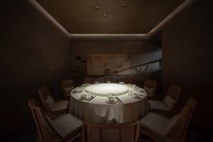 Modern restaurant interior with a round dining table, upholstered chairs, and soft lighting