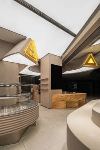 Modern restaurant interior with natural stone materials, featuring a sleek design with yellow signage.