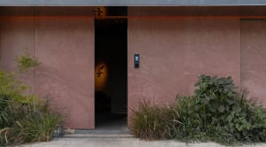 Modern entrance way made of marble material, featuring a black digital keypad for access and a dark interior space.