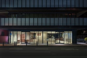 A modern storefront at night with glass walls and interior lighting.