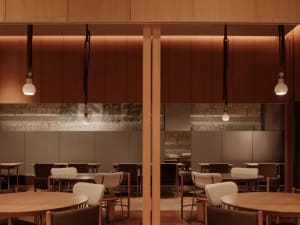 A restaurant interior with wooden ceiling features and cement walls.