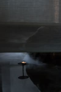 A minimalist interior design scene featuring a candle floating on water.
