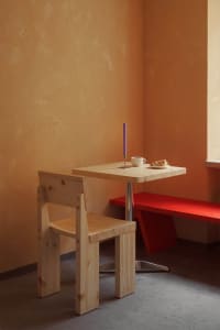 A modern cafe table made of wood with a metal base, featuring a candle and a pastry.