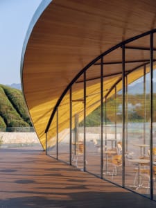 Modern restaurant interior featuring glass walls and wooden furniture.