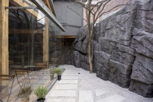 A modern coffee shop entrance featuring concrete walls, lighting, and seating.